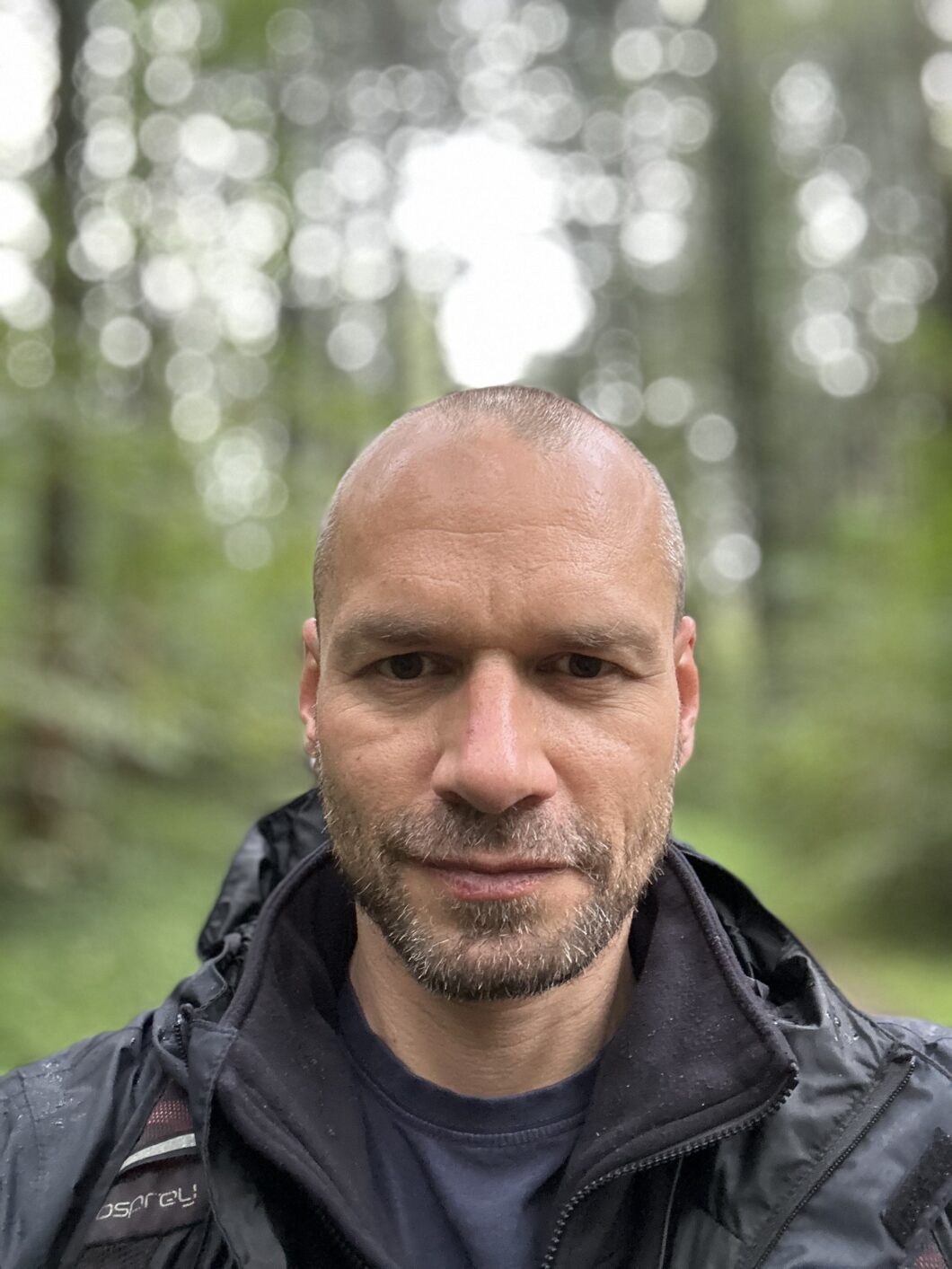 man, looking into camera, background forest