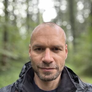 man, looking into camera, background forest