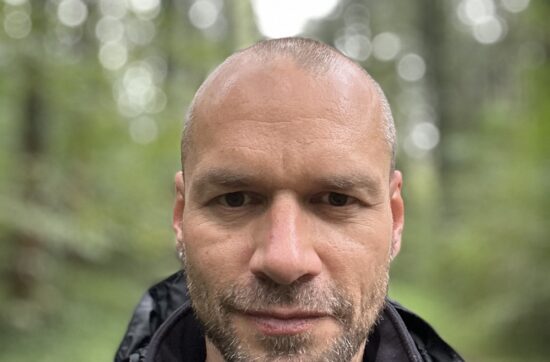 man, looking into camera, background forest